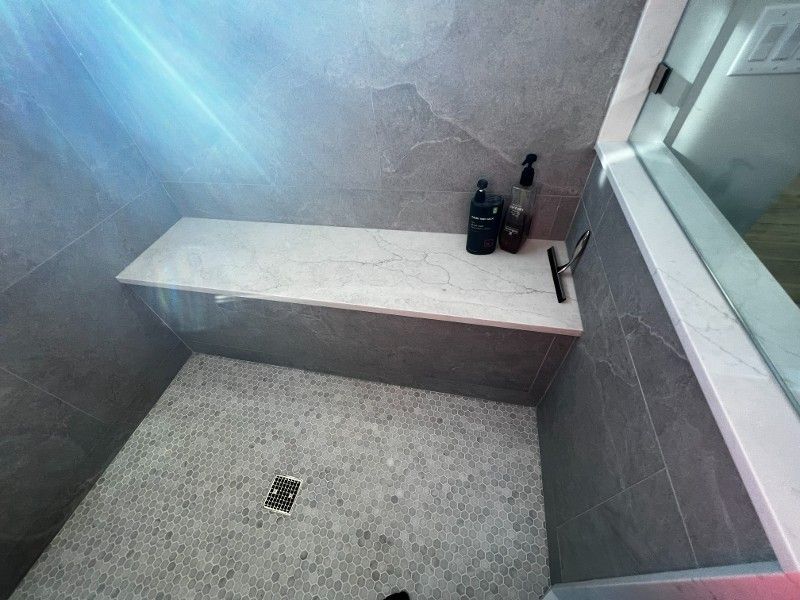 A walk in shower with a bench and a window