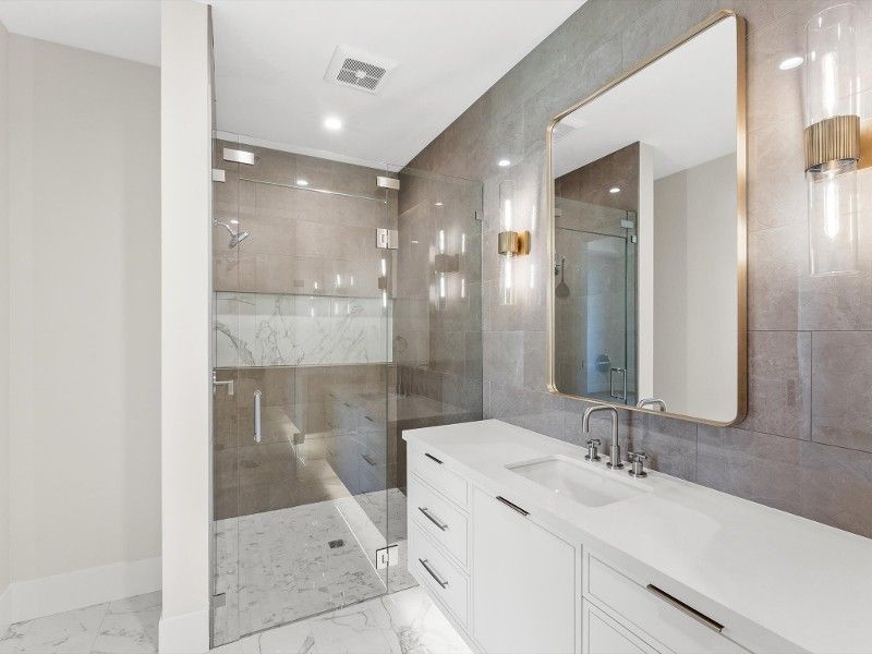 A bathroom with a sink , mirror and walk in shower.
