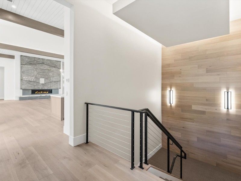 A staircase in a house with a wooden wall and a metal railing.