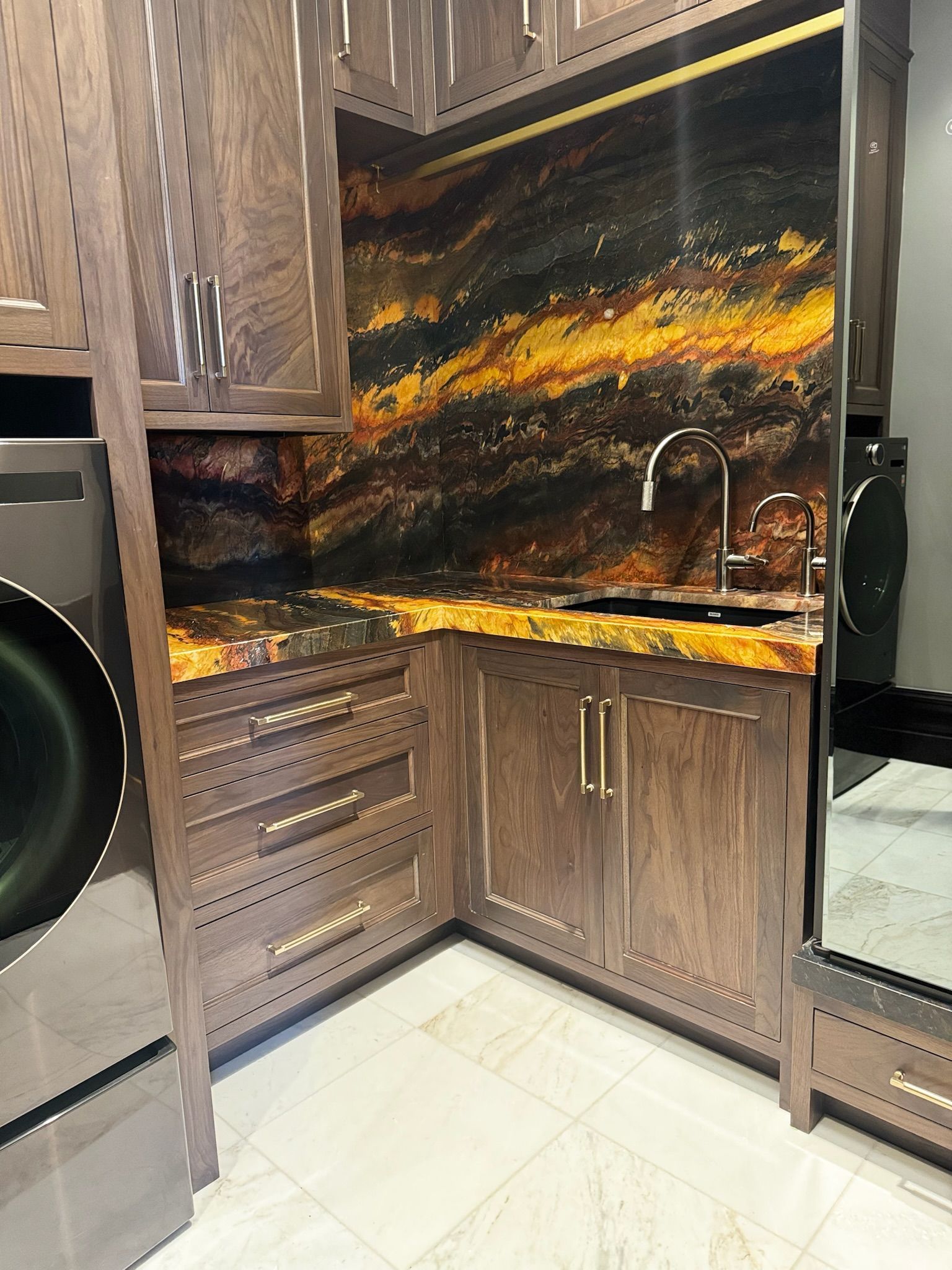 Laundry room with dark wood cabinets, a colorful backsplash, and a sink.
