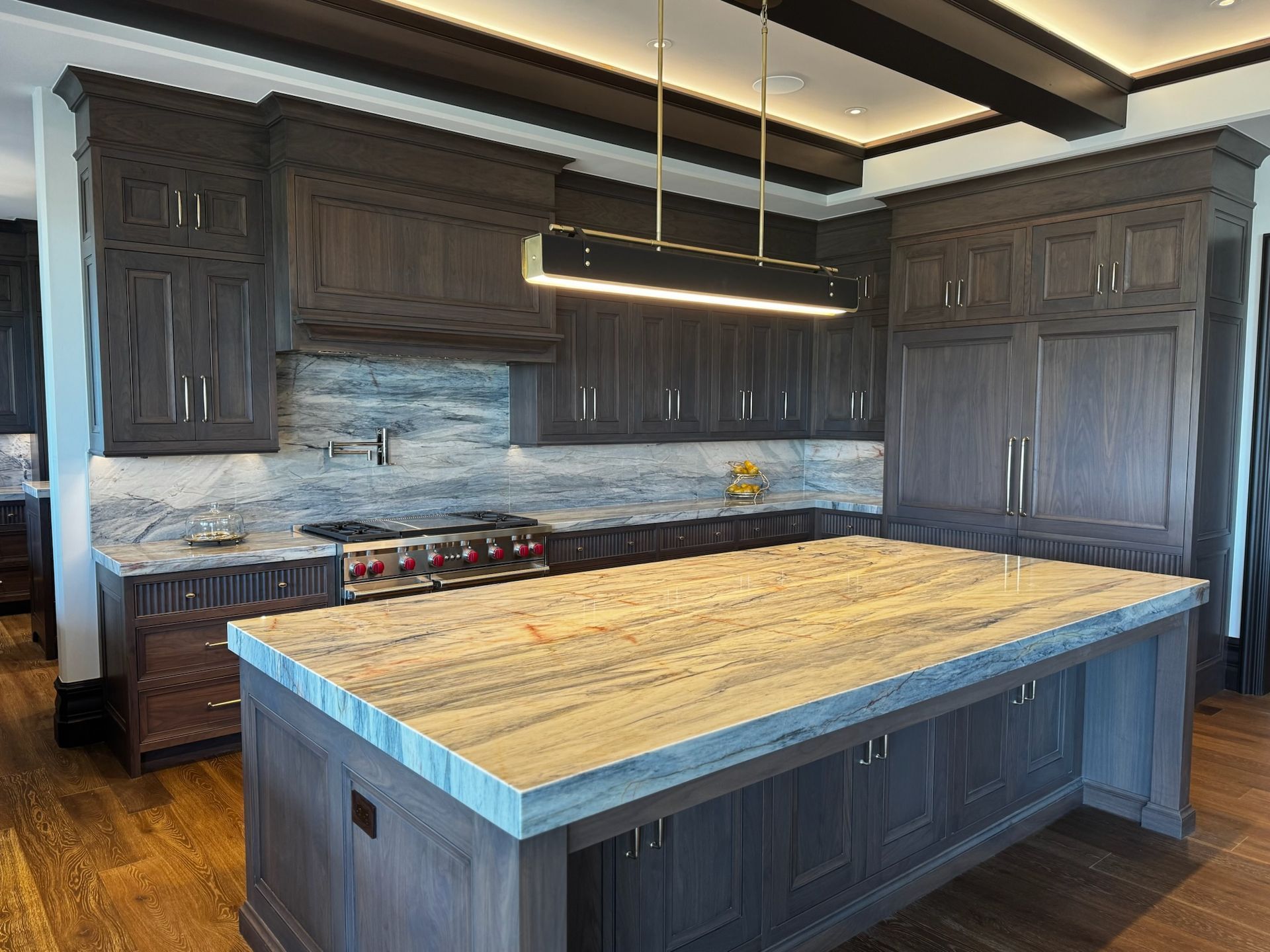 Dark wood kitchen with island, gray countertops, range, and modern lighting