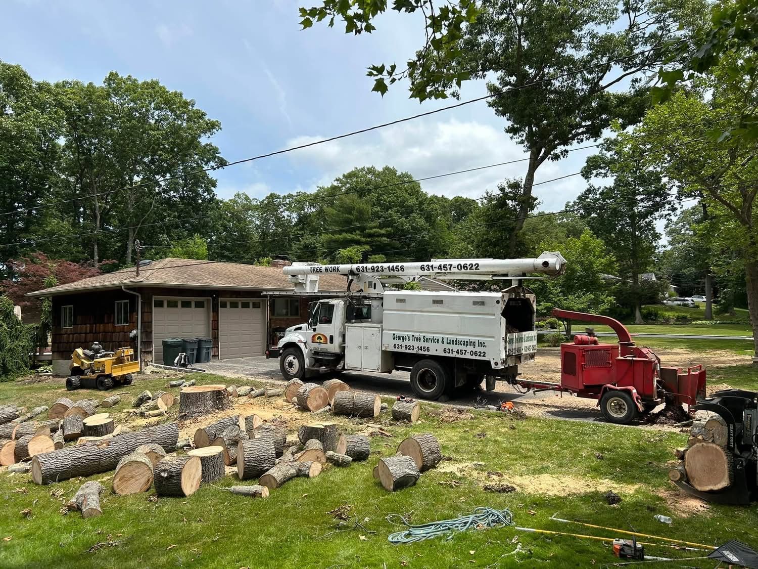A tree stump removal truck is parked in front of a house.