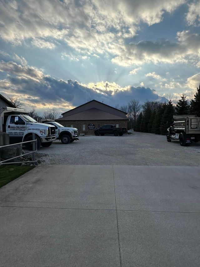 Wide driveway with trucks on both sides leading to a house under a cloudy sunset sky