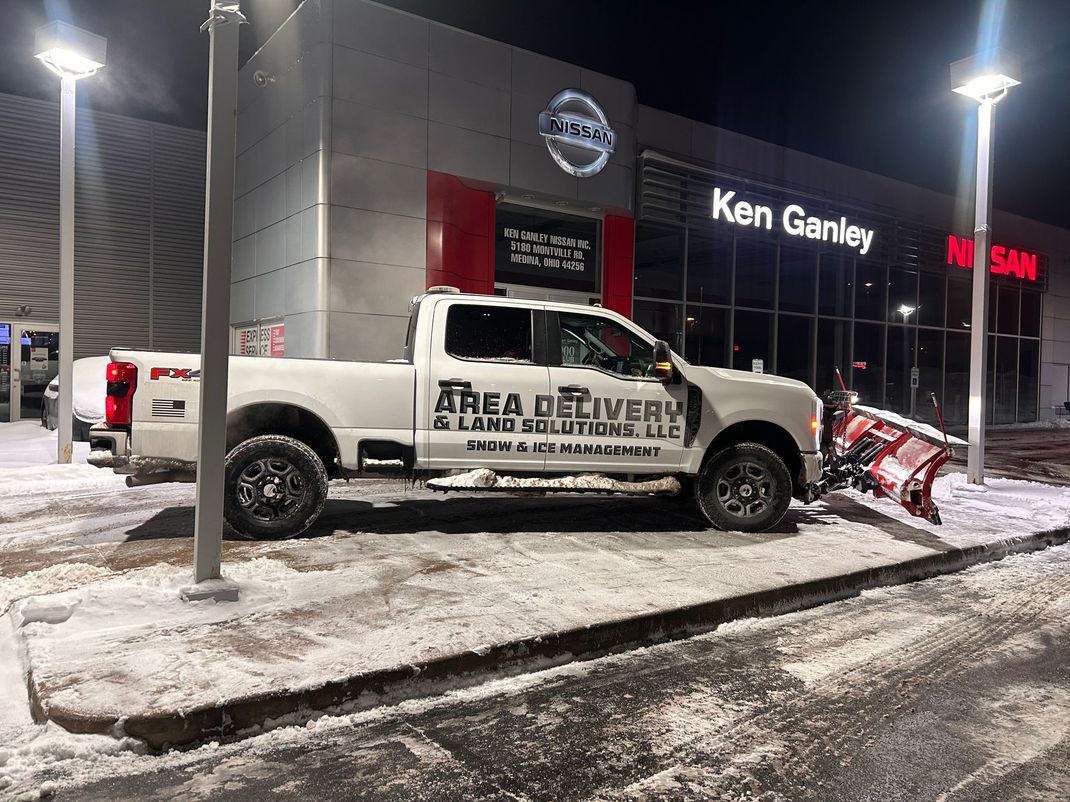 White pickup truck parked outside Ken Ganley dealership at night, with snow on the ground and a tow truck nearby