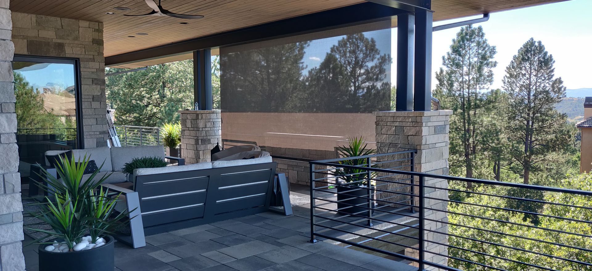 Patio with seating, stone columns, and trees in the background.