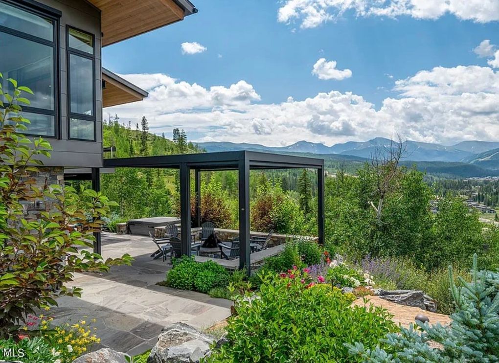 Modern home patio with garden seating, lush greenery, and mountain views under a blue sky