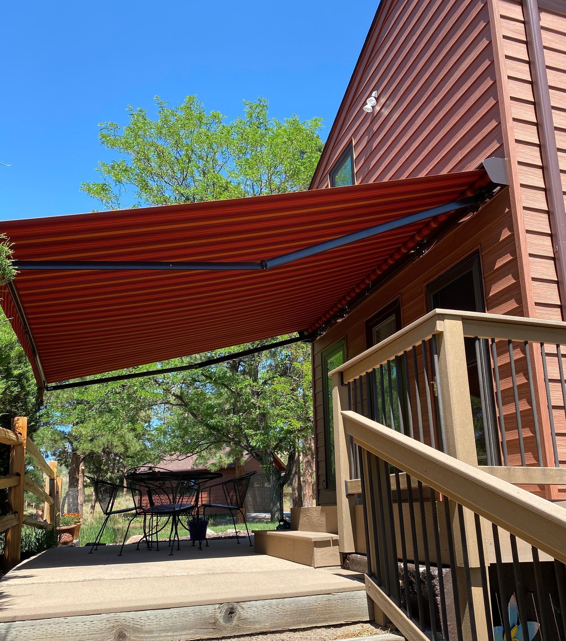 Red and white striped awning extended over a wooden deck attached to a cabin-style building.
