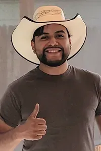 Man in cowboy hat gives thumbs-up, smiling.