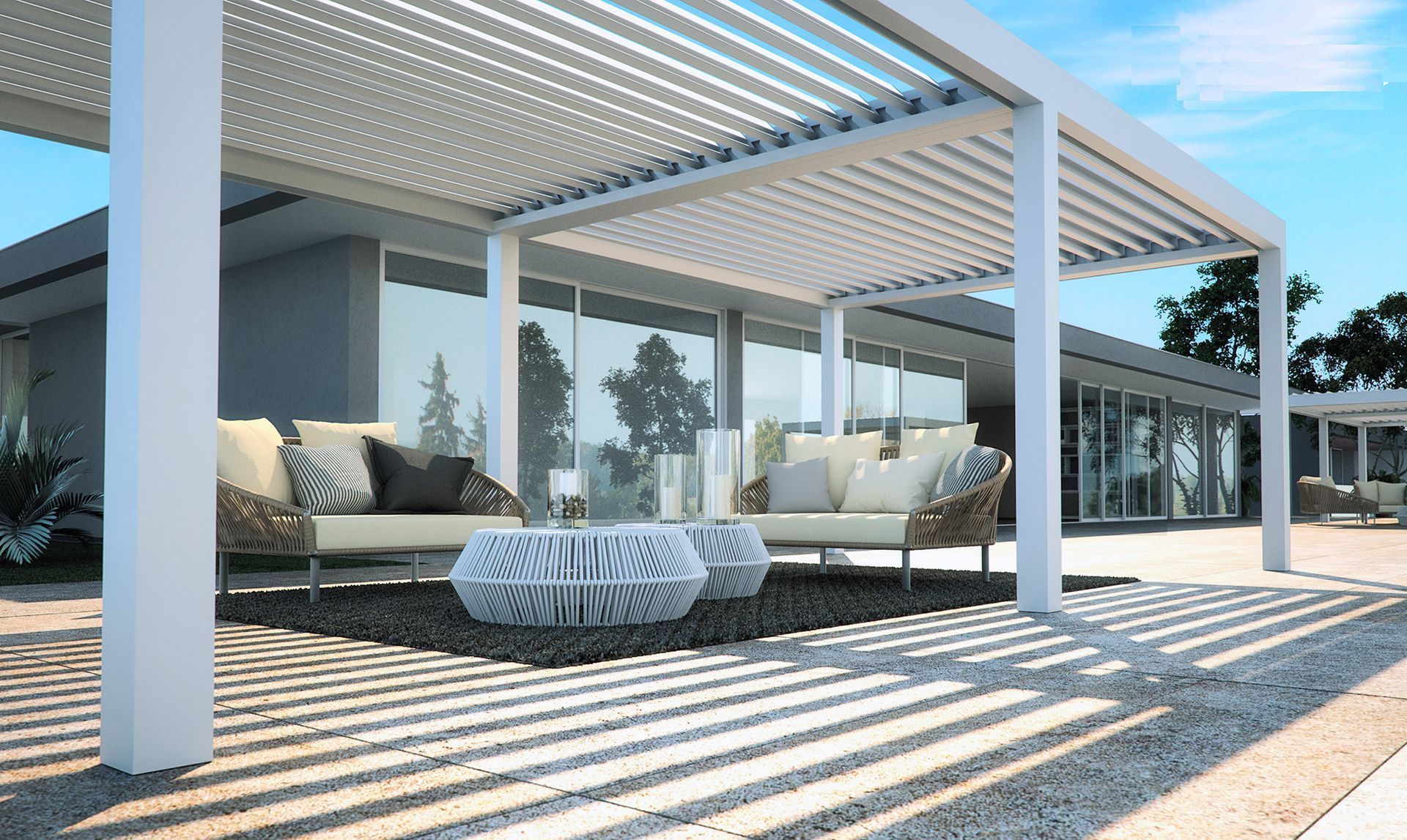 Patio with white pergola, seating, and coffee table casting shadows on the ground.