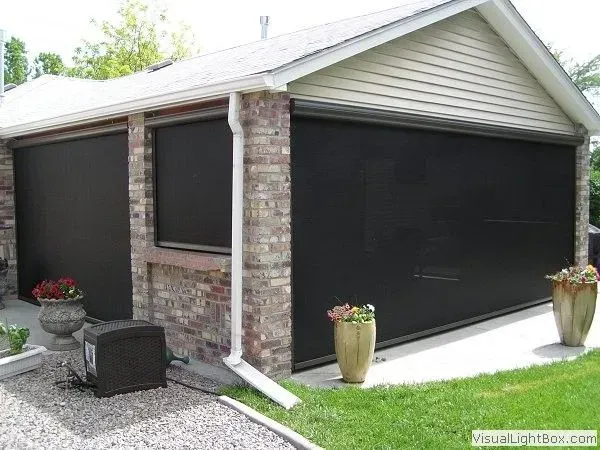 Exterior view of a brick building with three large black retractable sun shades.