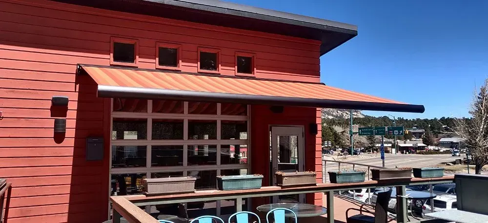 Red building with awning and outdoor seating. Sunny day.