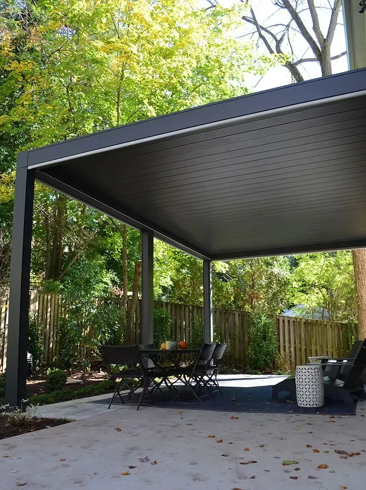 Gray modern pergola with a table and chairs in a backyard setting.