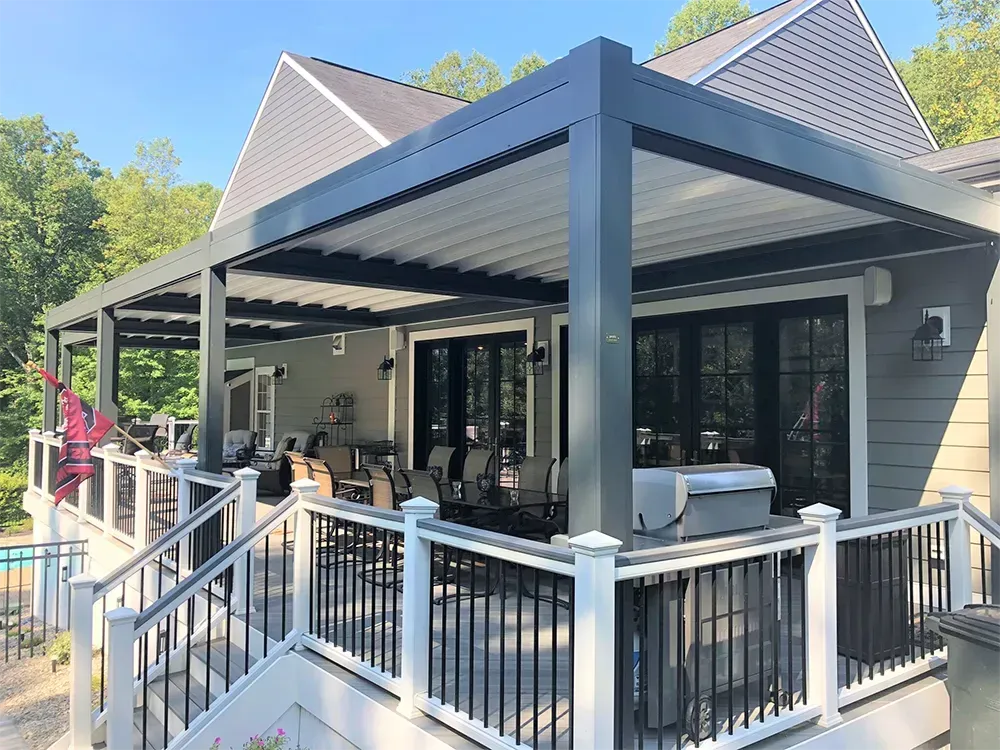 Patio with dark gray pergola, white railing, and house with black doors.