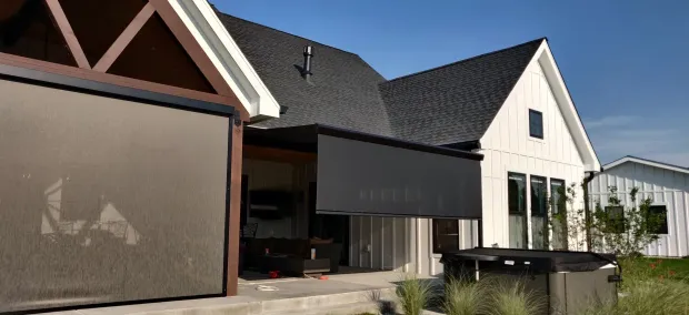 Modern white building with a dark awning, garage, and landscaped front entrance in daylight