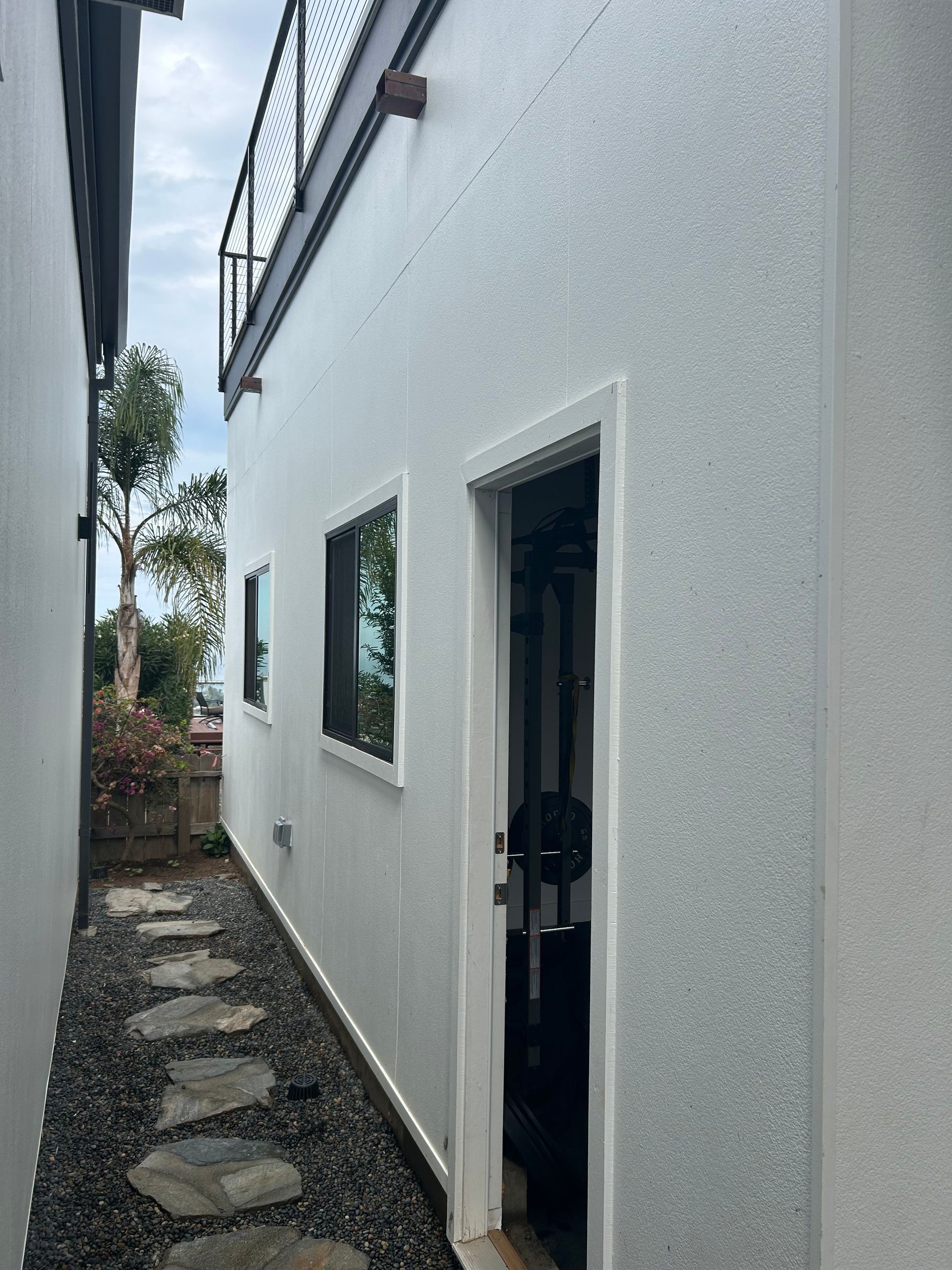 Pathway between two white buildings, leading to a door; small rocks and stepping stones.