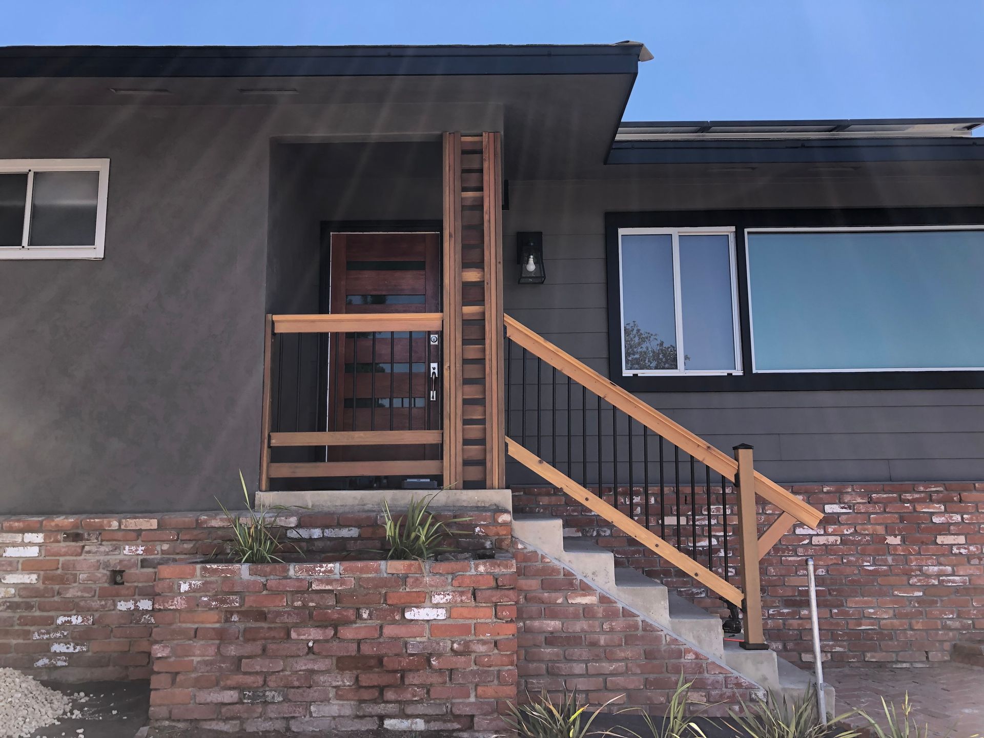 A gray house with a brick base and wooden porch with a stair and a handicap ramp.