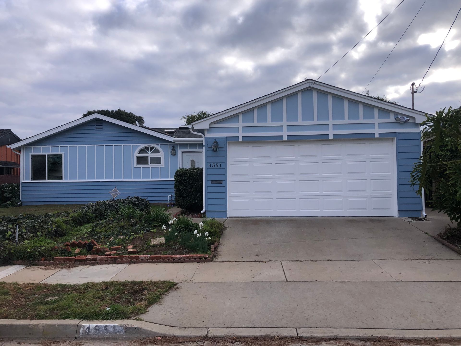 Blue house with white garage door, on a cloudy day.