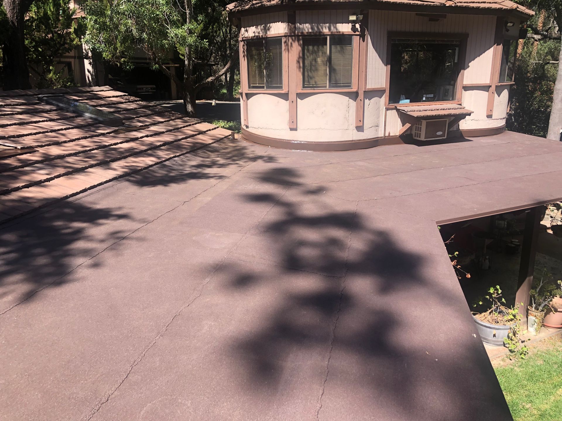 Brown flat roof with an octagonal building and shadows from trees.