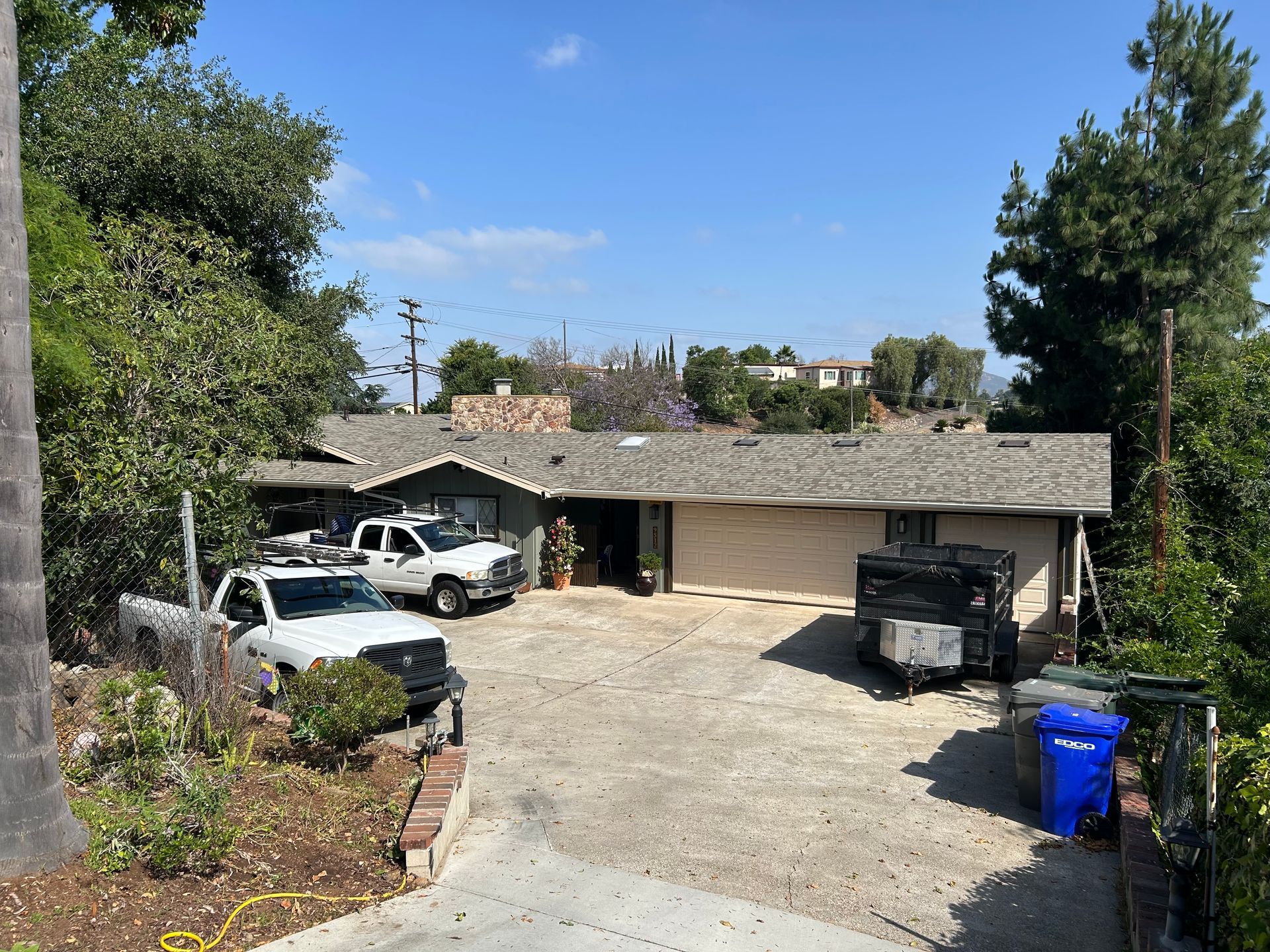 A single-story house with two service trucks parked in front on a sunny day.