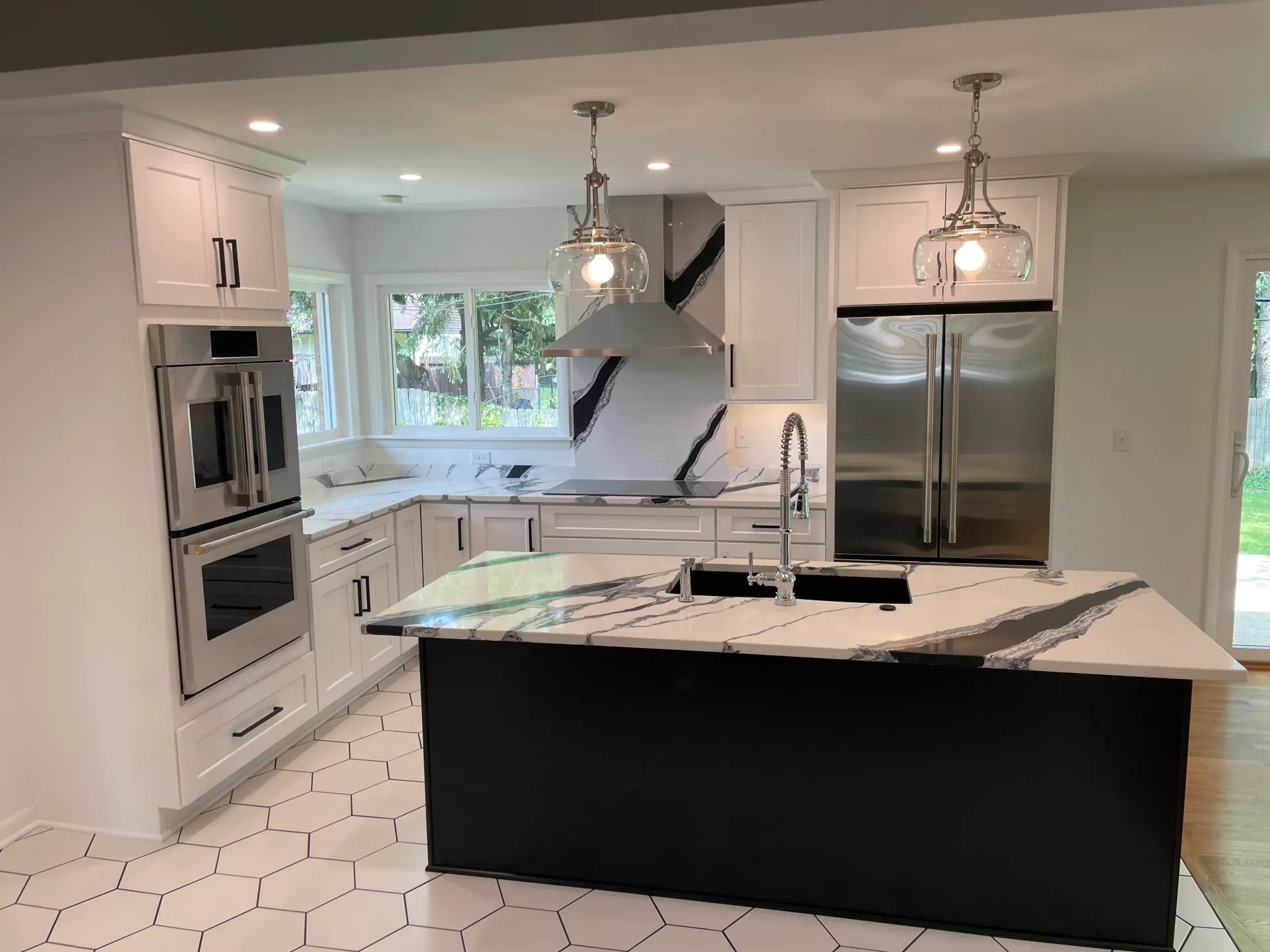 Modern kitchen with white cabinets, black island, stainless steel appliances, and quartz countertops.