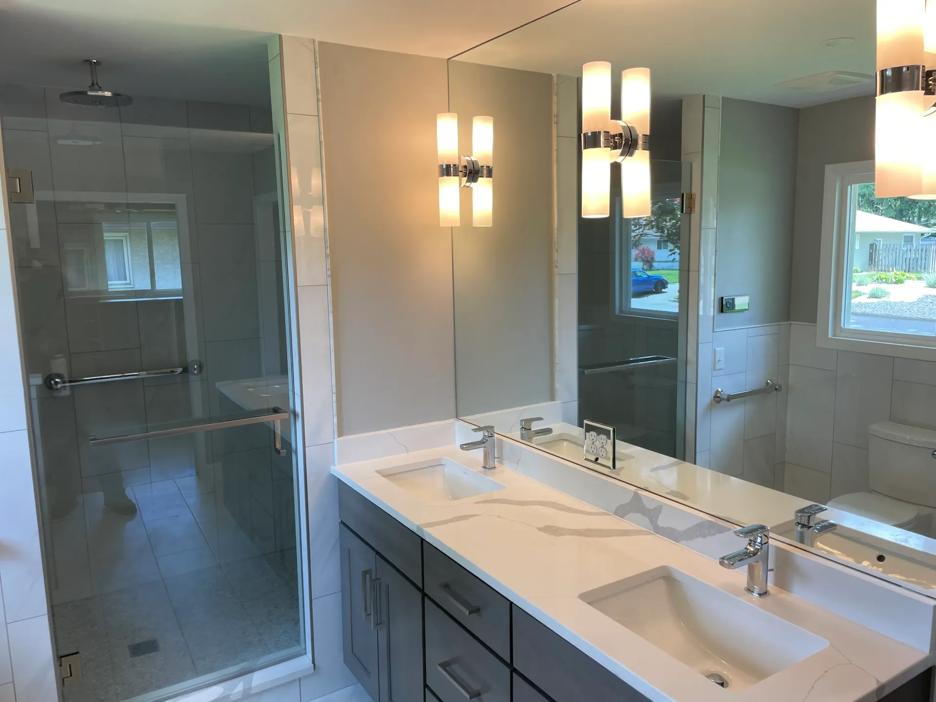 Modern bathroom with a glass shower, double vanity, and bright overhead lights.
