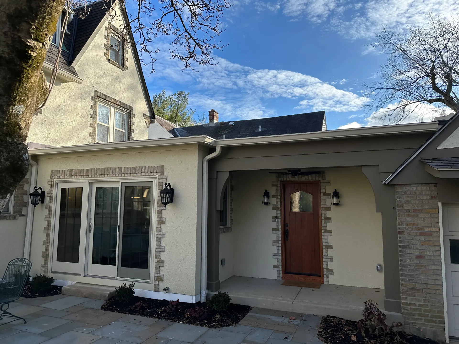 House exterior with stucco and stone accents, covered porch, and blue sky.
