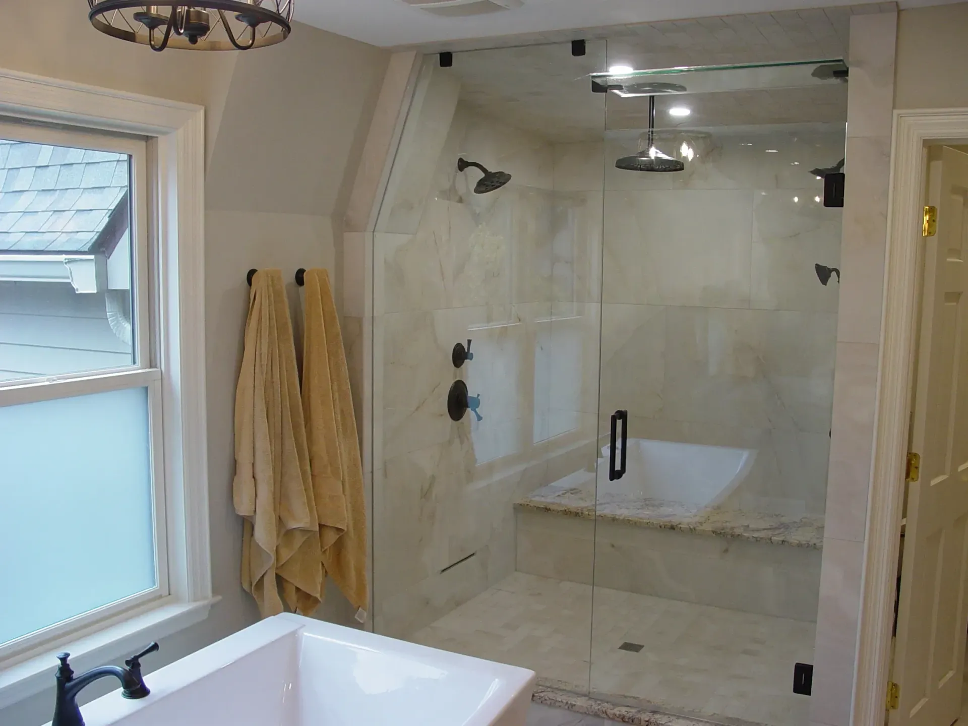 Bathroom with a glass shower, white tub, and tan walls.