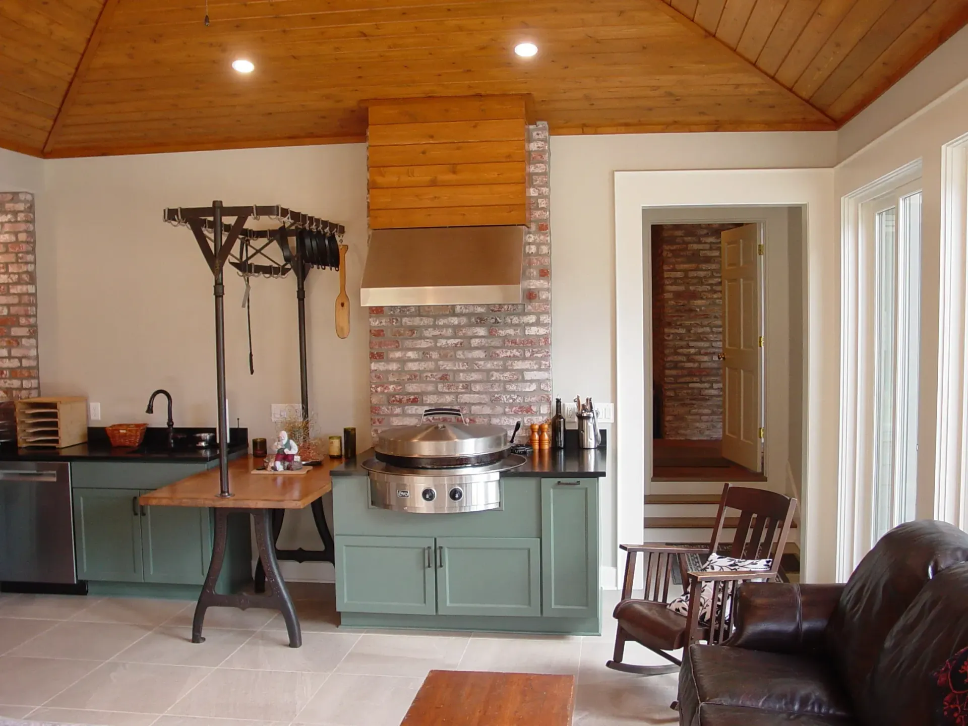 Kitchen with blue cabinets, brick accents, stainless steel appliances, and wood ceiling.