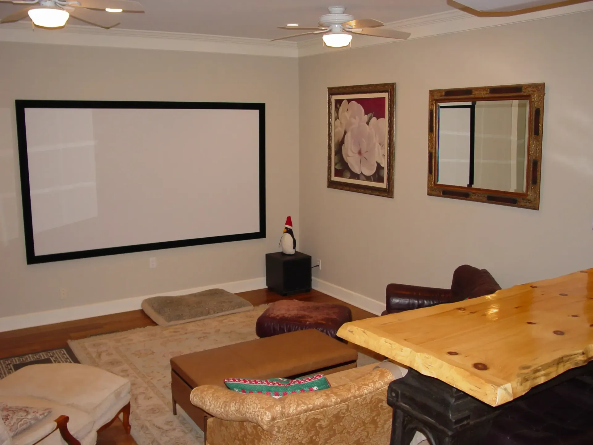 Home theater with a screen, bar, and seating. Beige walls, wood accents, and artwork.