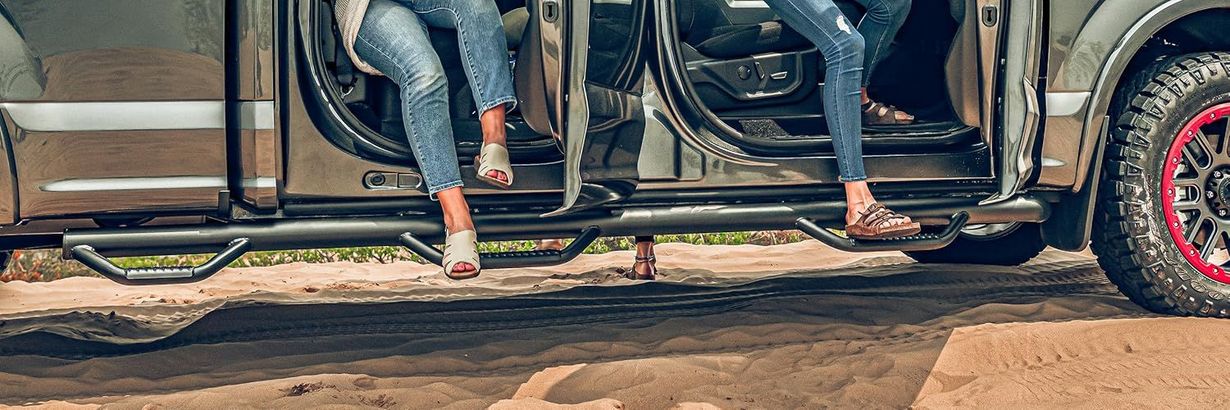 Two people sitting in an open vehicle, with one foot extended near the ground.