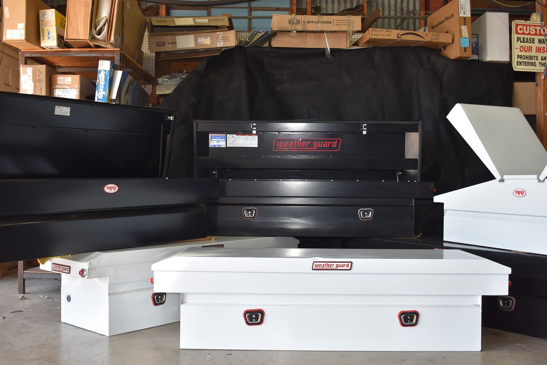 Stacked black and white CNC machine parts in a workshop or garage space.