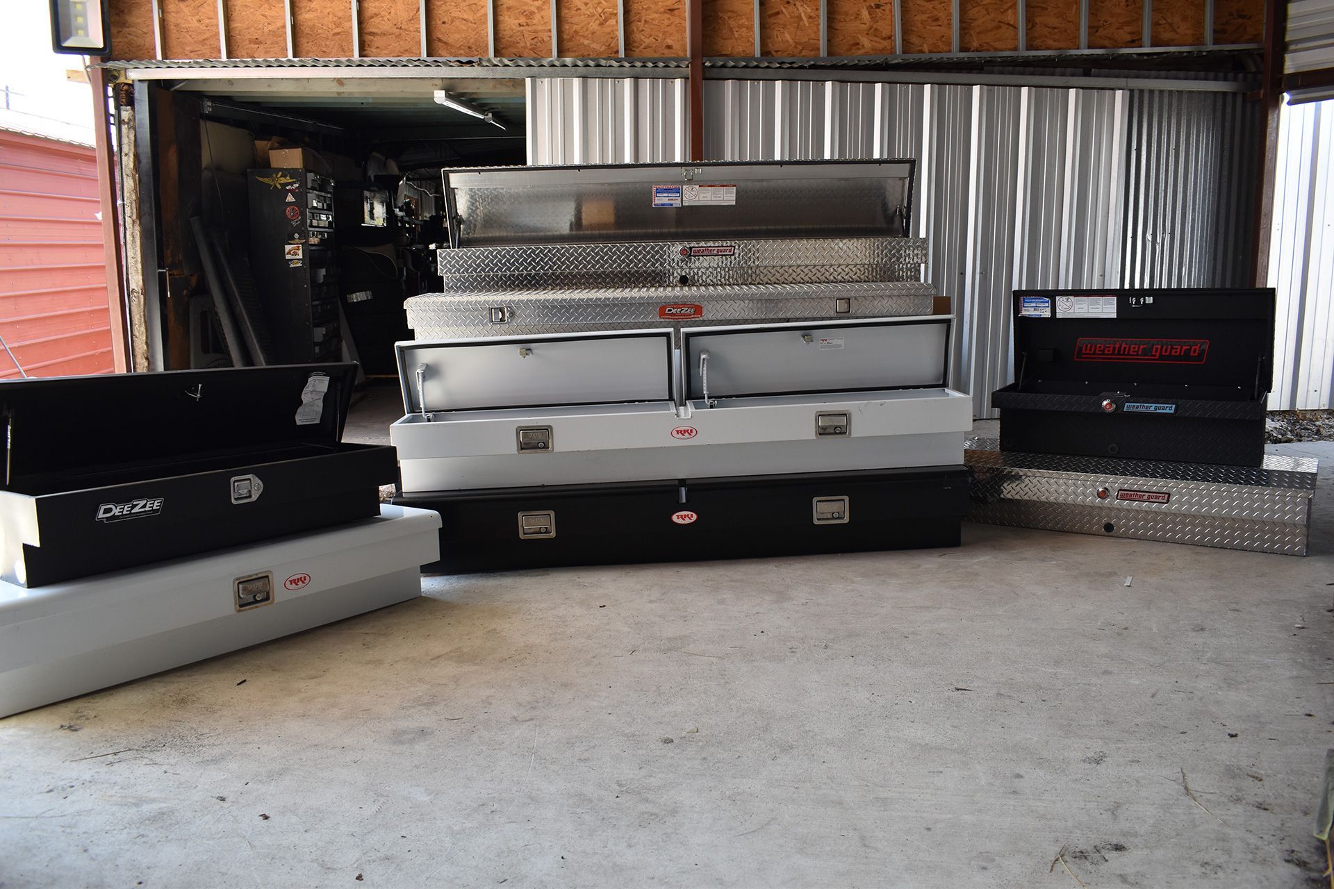Garage filled with stacked silver and black truck beds and car parts