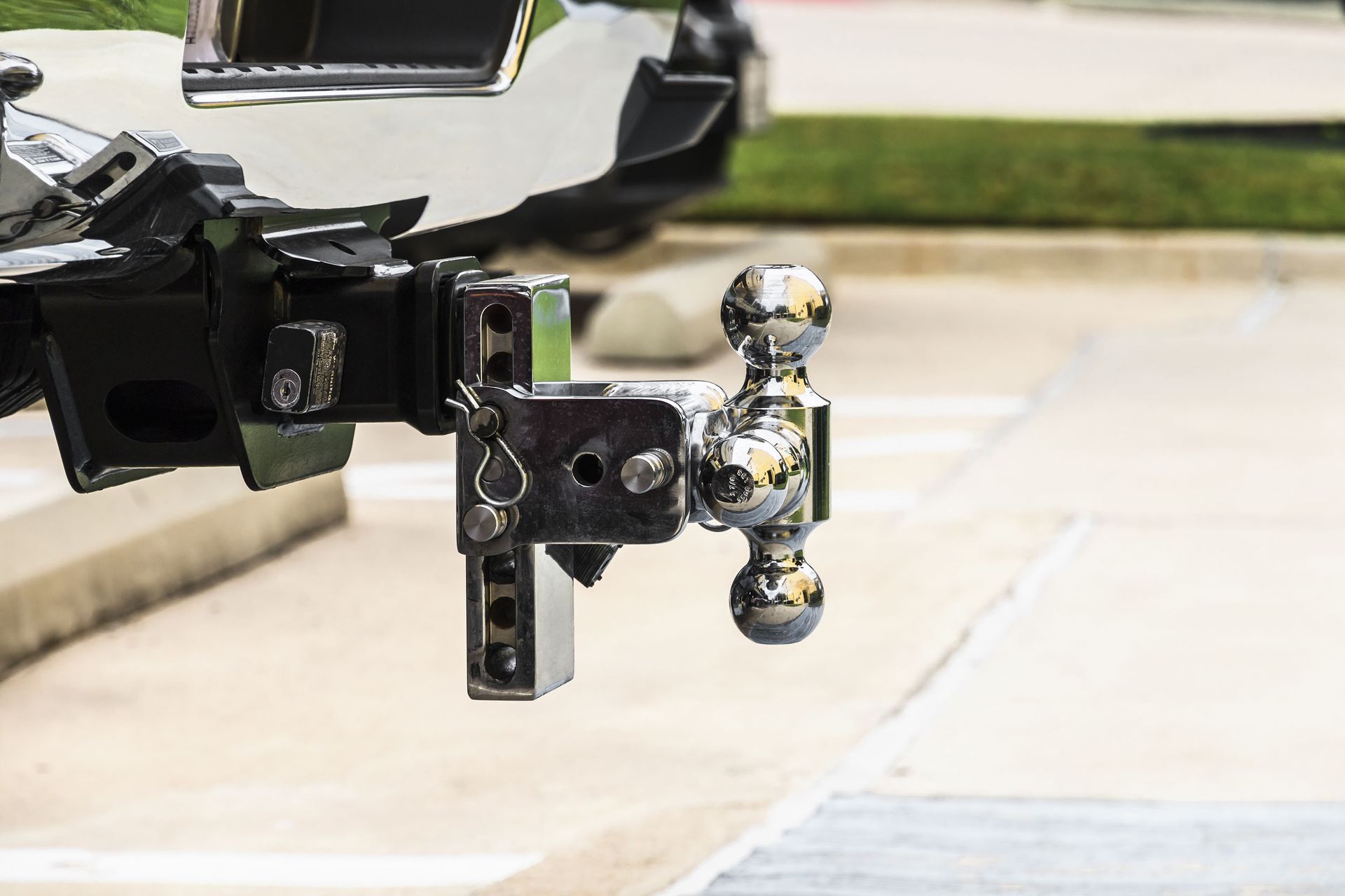 Chrome trailer hitch with a shiny tow ball attached to a black vehicle mount outdoors