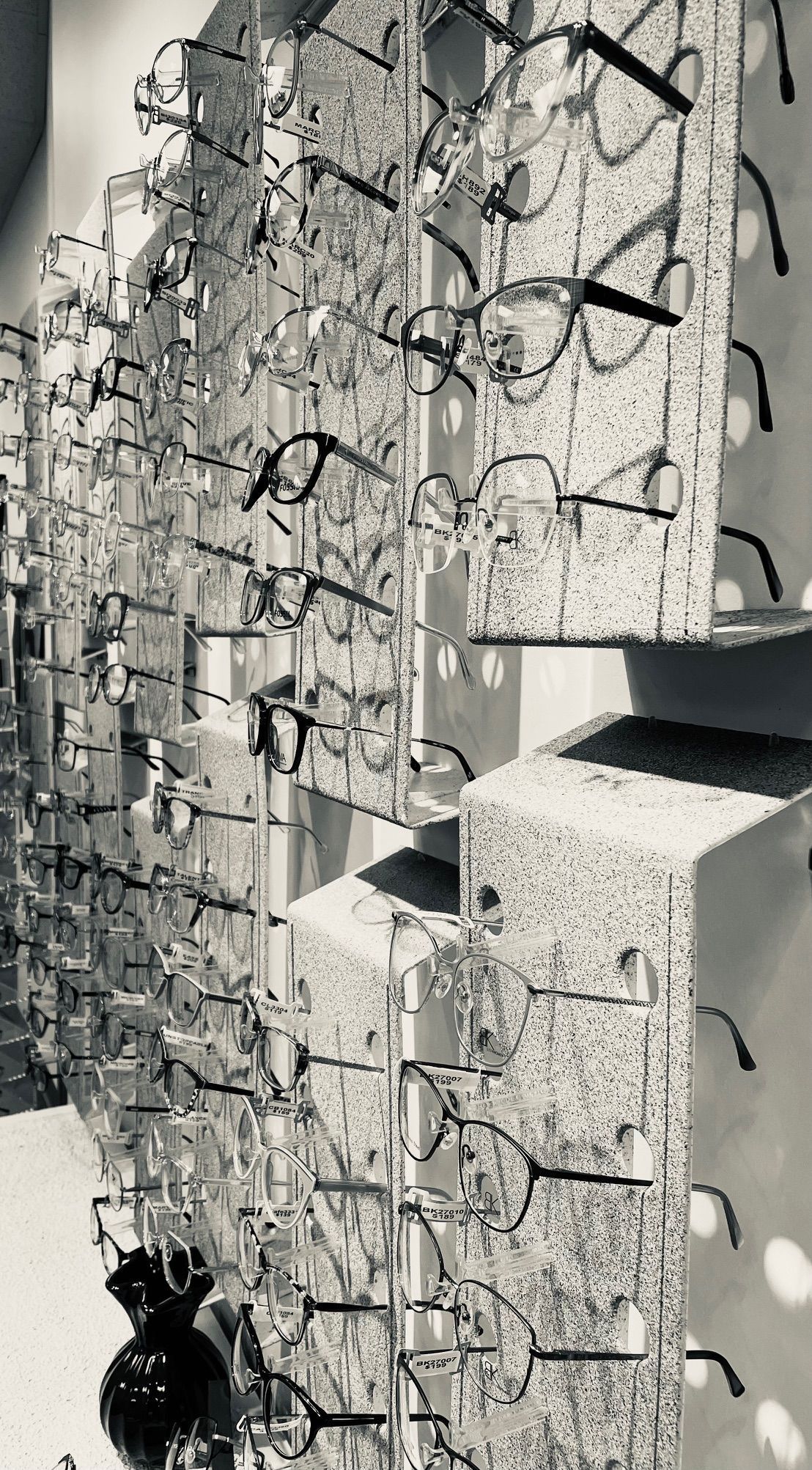 A black and white photo of a row of glasses hanging on a wall.