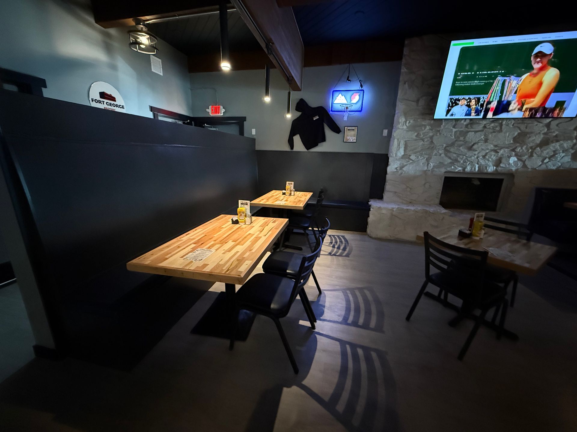Restaurant interior with tables, chairs, TV, and stone fireplace.