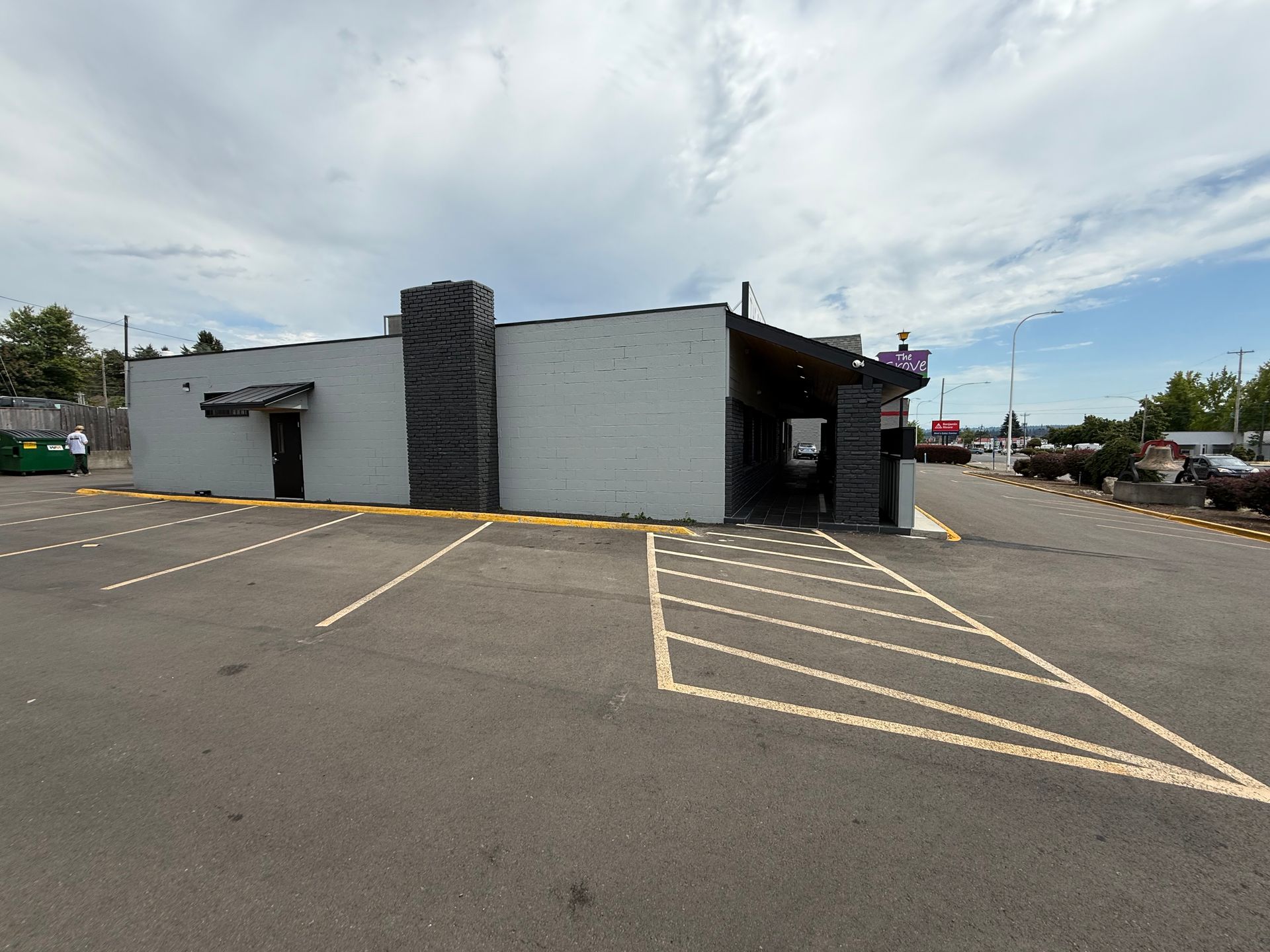Gray building with black accents in a parking lot on a cloudy day.