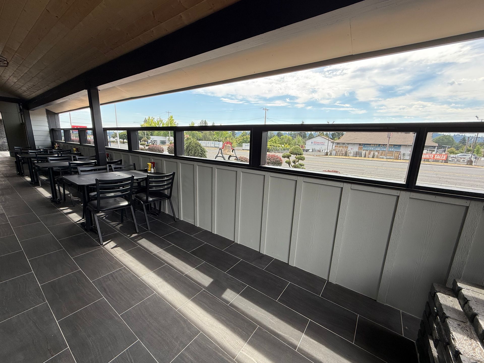 Outdoor restaurant seating with tables and chairs overlooking a parking lot.