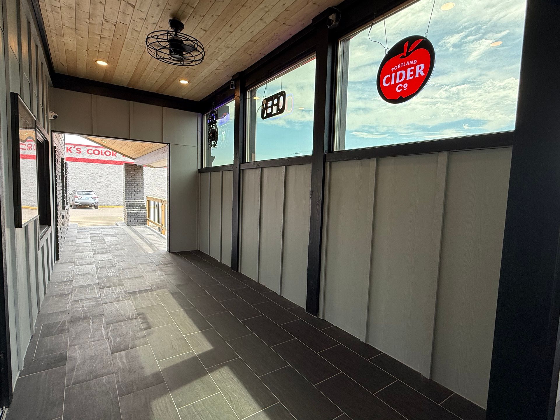 Narrow hallway with wood-look floors, large windows, and a door leading outside; cider logo visible.