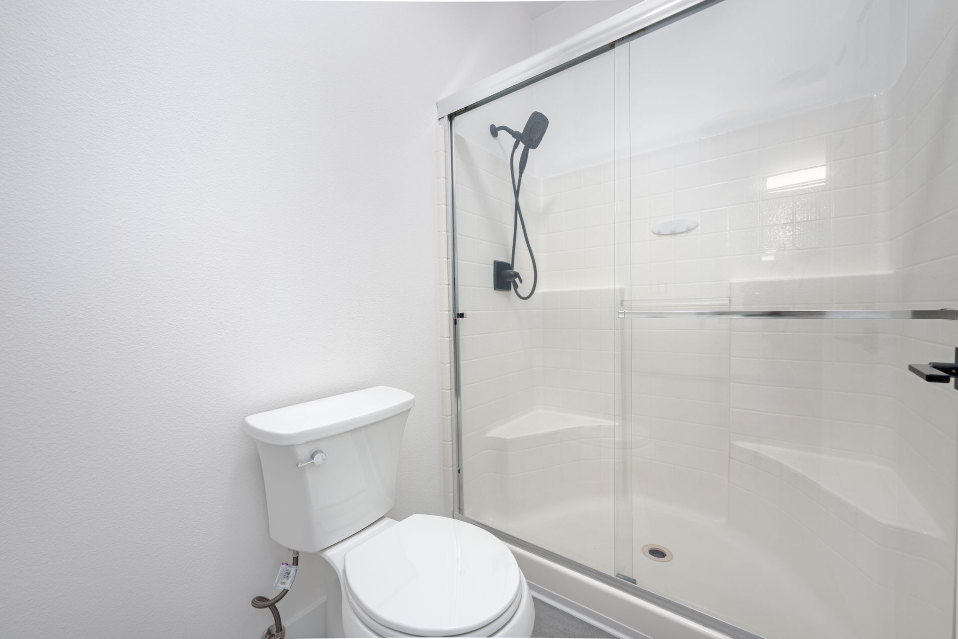 White bathroom with a toilet and glass shower enclosure.