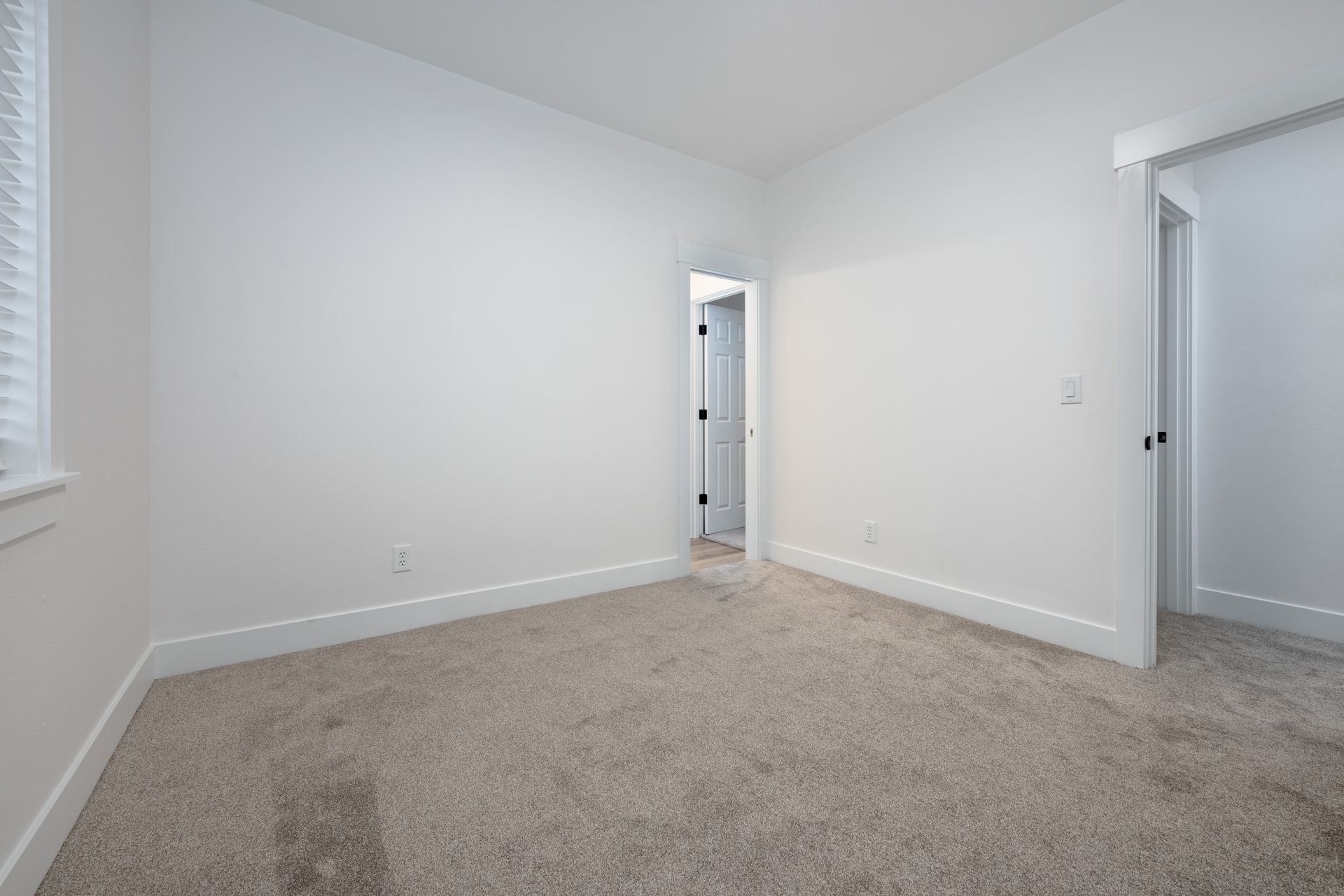 Empty room with beige carpet, white walls, and two open doorways.