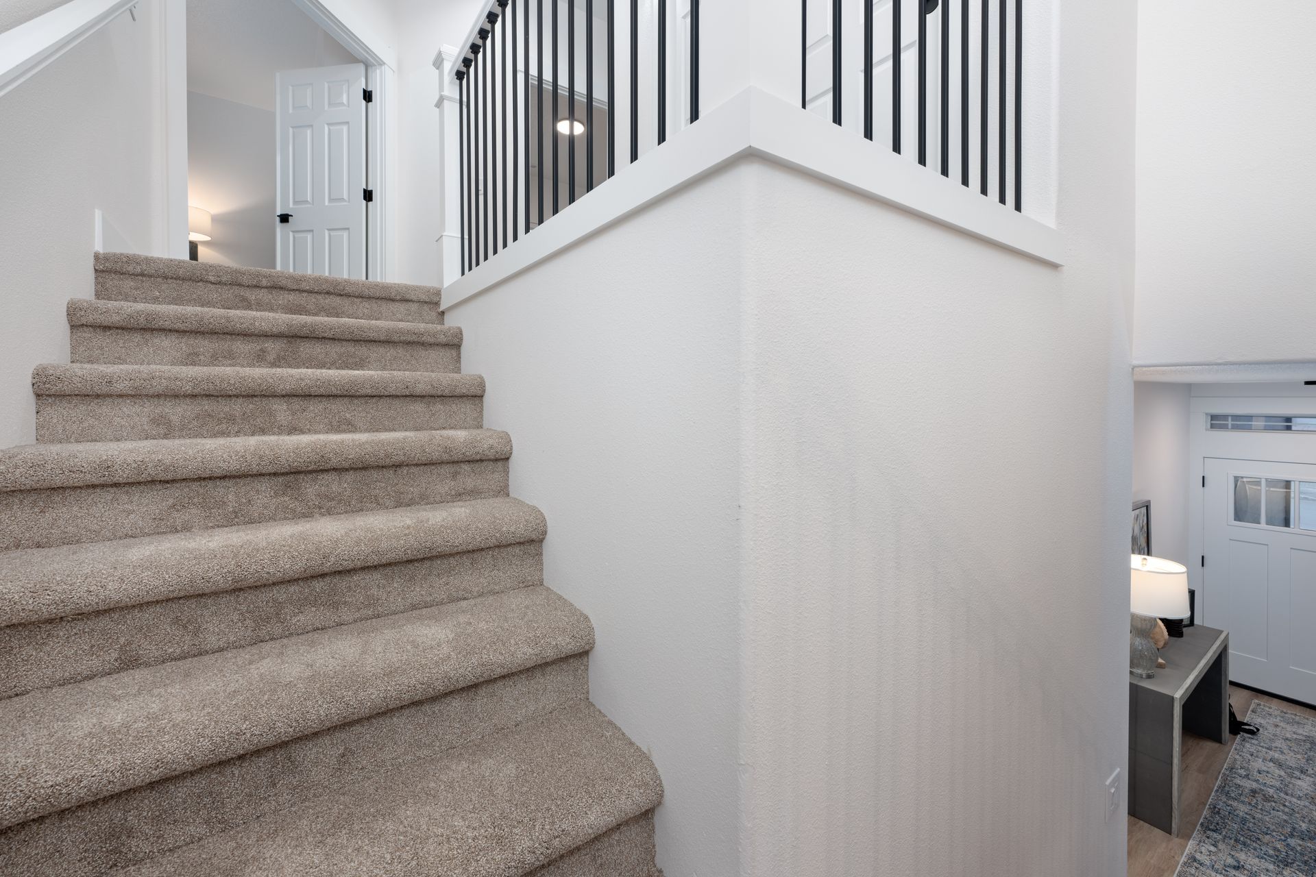 Staircase with carpet steps, leading up to a second story. White walls, black railing.