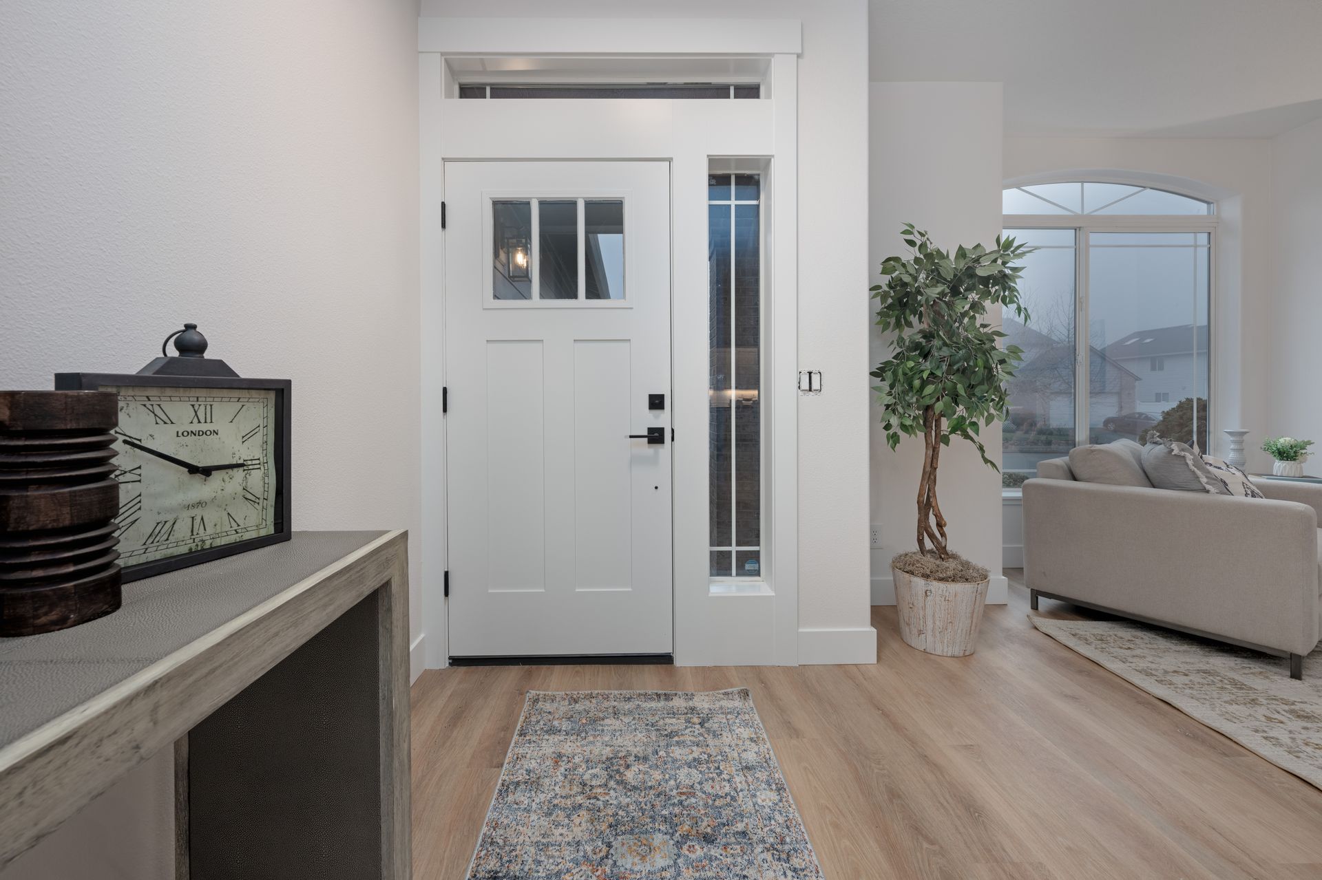 Entryway: White door with sidelight, leading to a living room with a sofa and mountain view.