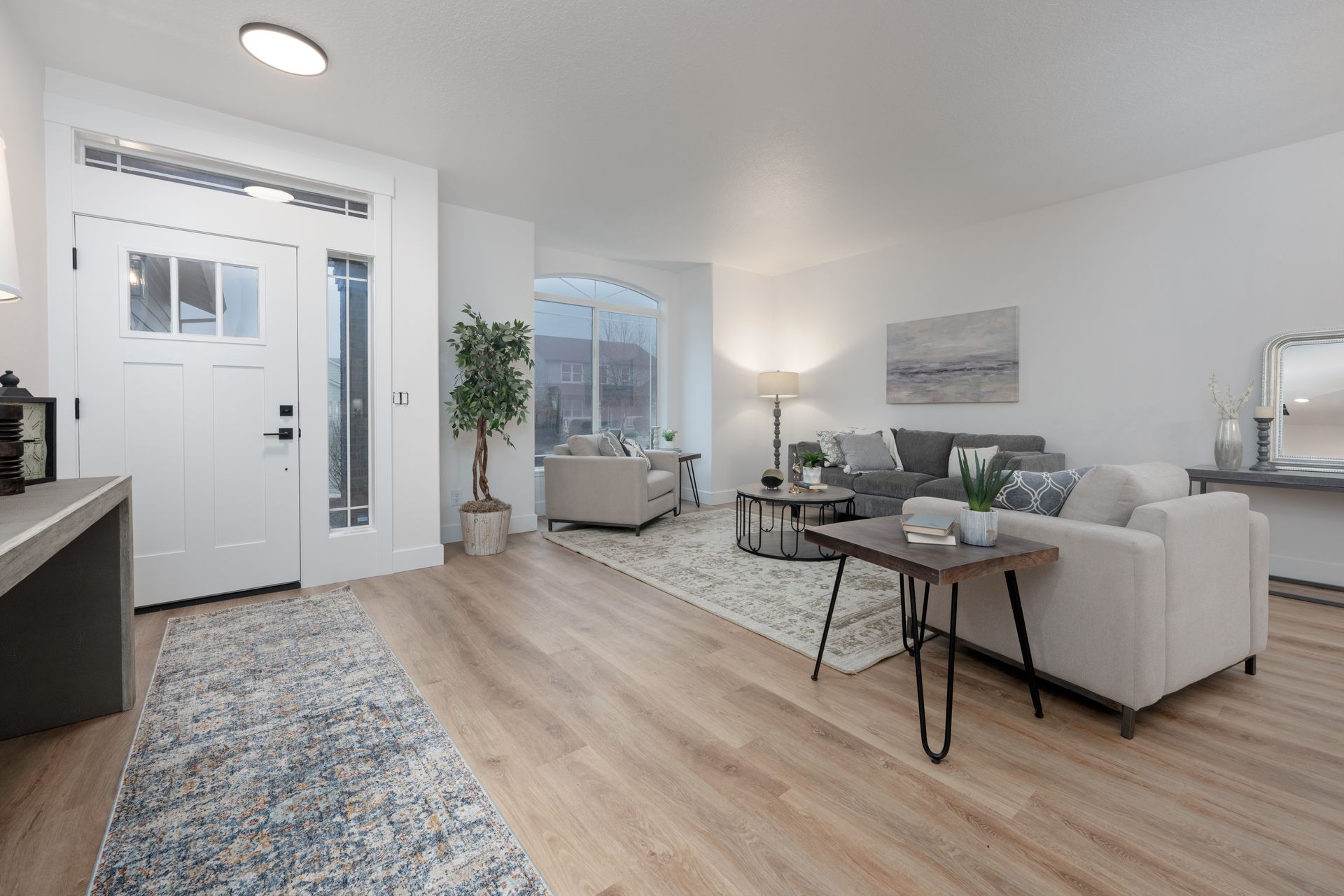 Bright, airy living room with light wood floors, white walls, and neutral-toned furniture.