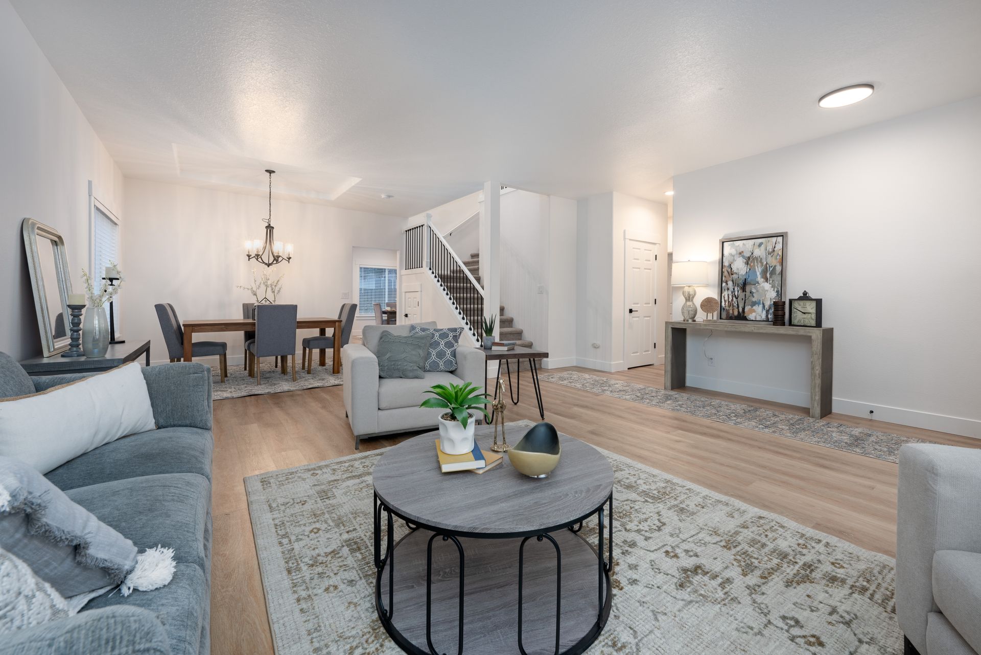 Living room with sofa, dining table, and stairs; neutral colors.