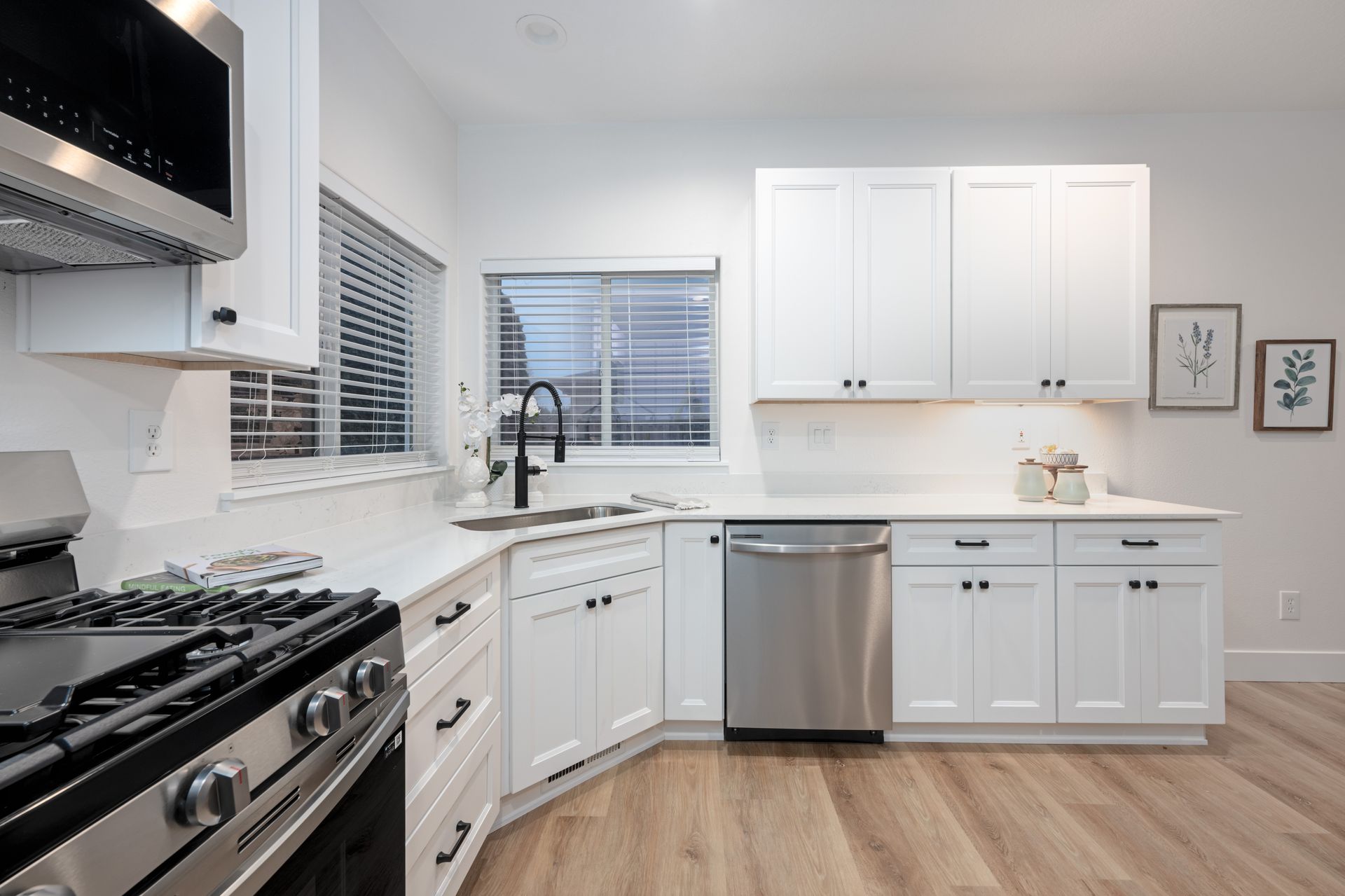 White kitchen with stainless steel appliances and light wood floors.