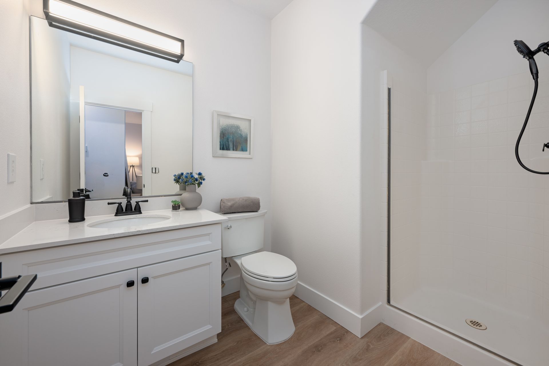 White bathroom with a sink, toilet, and shower.