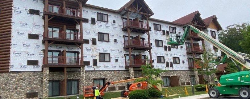 A large apartment building is being remodeled with a crane.
