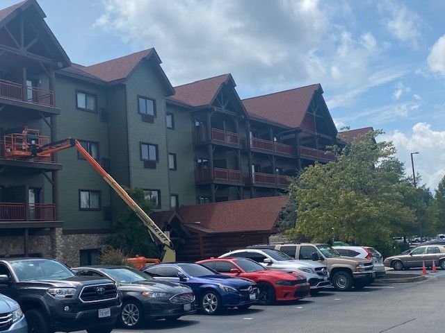 A row of cars are parked in front of a large building