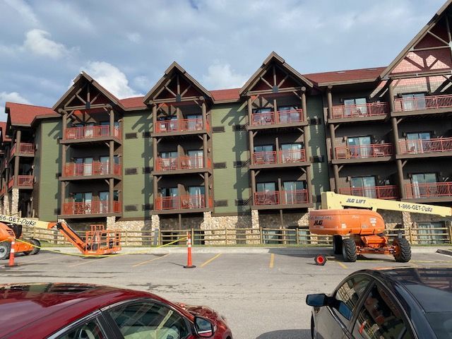 A red car is parked in front of a large building