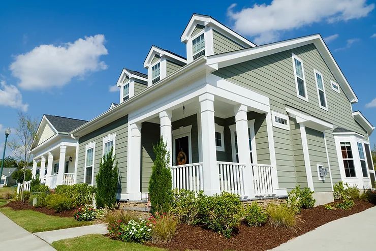 A large house with a porch and a blue sky in the background